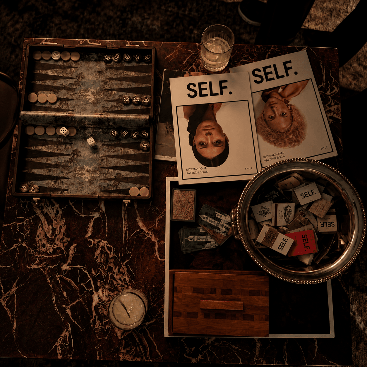 SELF. magazines and backgammon on a marble table